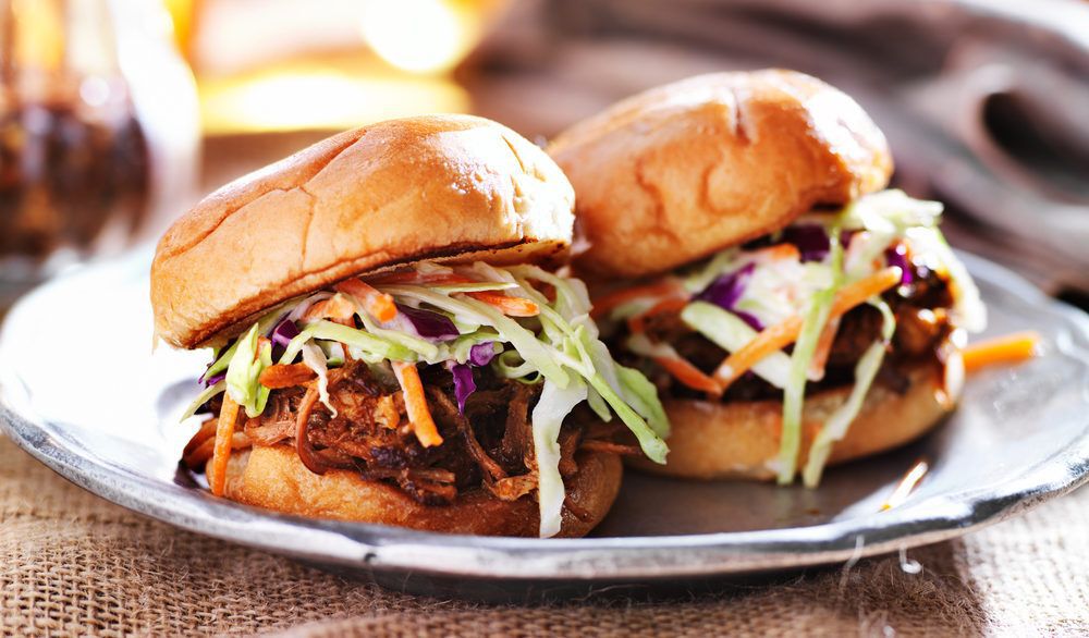 Beef sliders with a green slaw on a white plate.