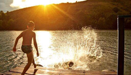Kids jumping into a lake at sunset.