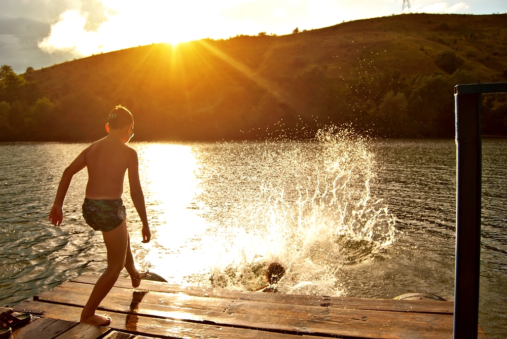 Kids jumping into a lake at sunset.