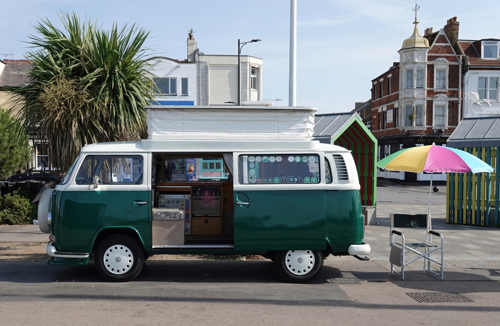 Green VW van parked on the side of a road.