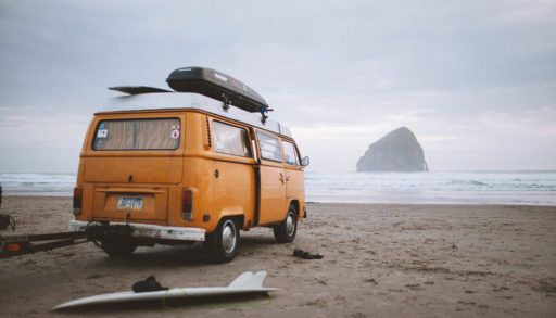VW van in front of water, with surfboards