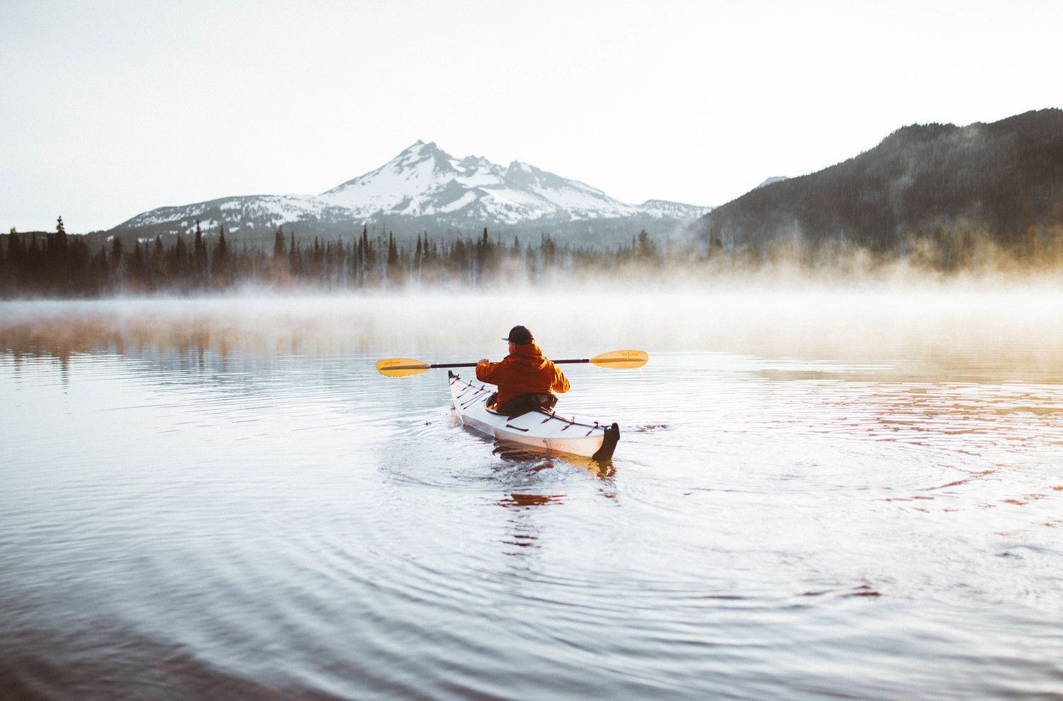 person kayaking on misty lake