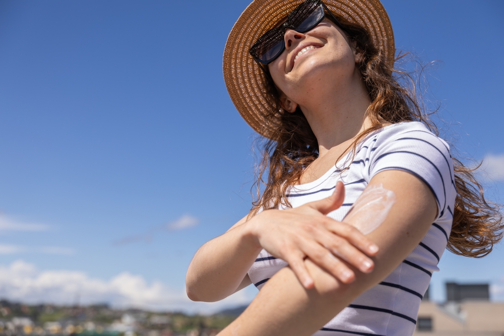 A woman applying sunscreen to her arm.