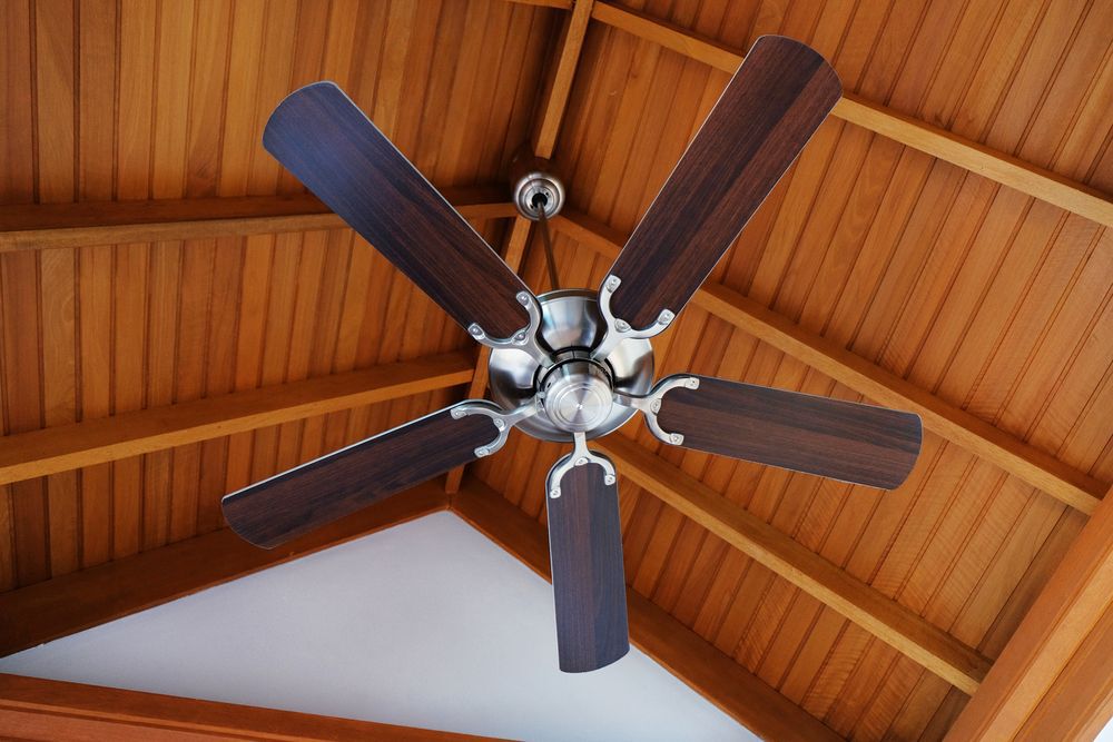 Cottage ceiling fan attached to a wooden A-frame roof.