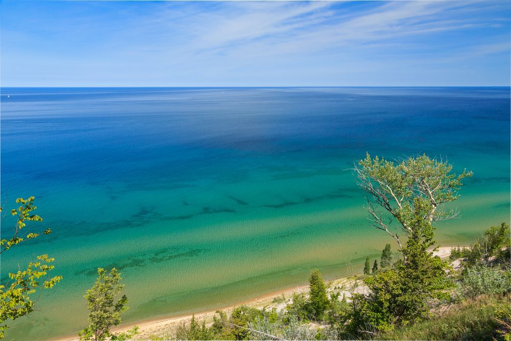 Ariel view of Lake Michigan with a shoreline of trees and sand.