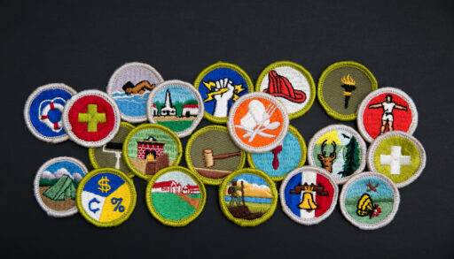 A pile of brightly coloured merit badges on a black background.