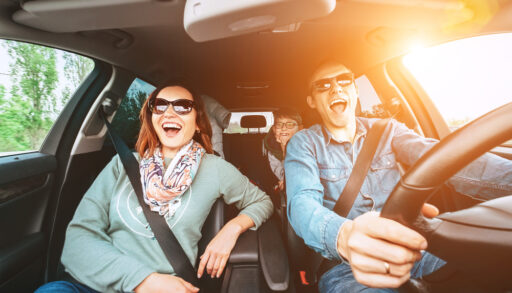 Couple and a child singing in a car on a road trip.