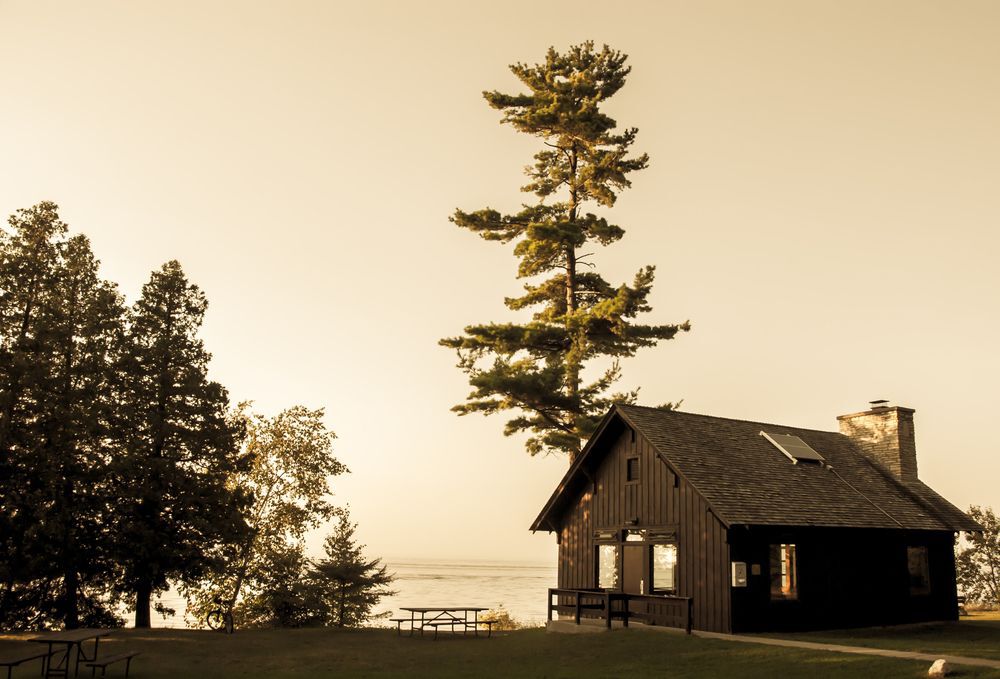 Wooden country home right by a lake and surrounded by trees.