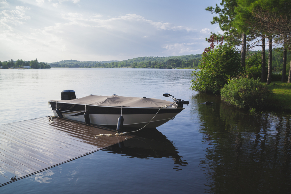 Covered motor boat on a lake tied to a dock.