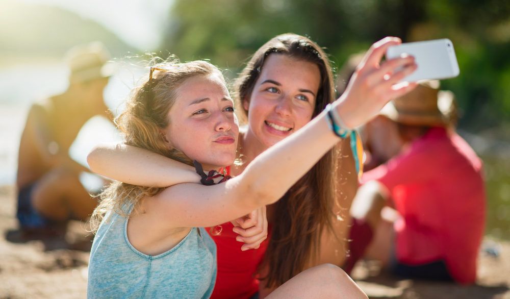 Two teen girls taking a selfie on a beach.