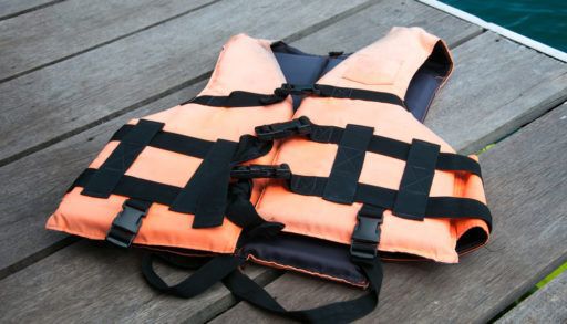 Orange life jacket laying on a wooden dock.