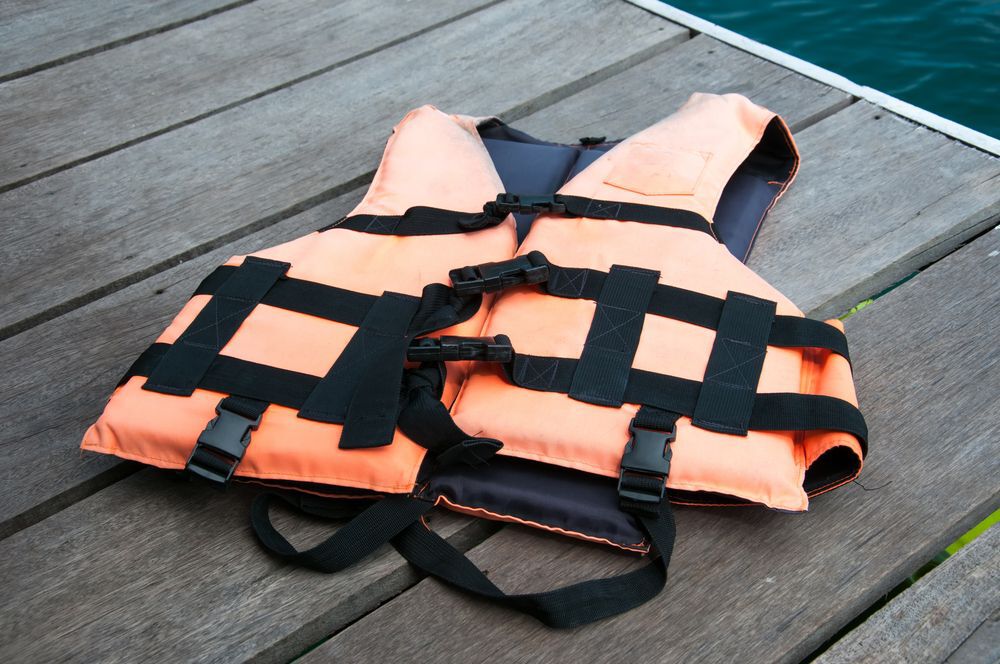Orange life jacket laying on a wooden dock.