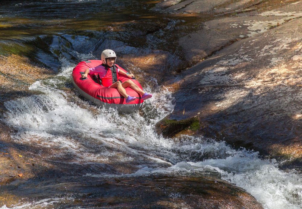 Kid tubing in a red tube in a river.