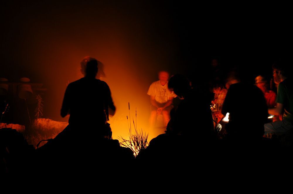 Silhouettes of people sitting around a campfire.