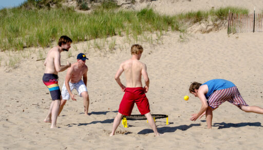 Guys playing spike ball on the beach.