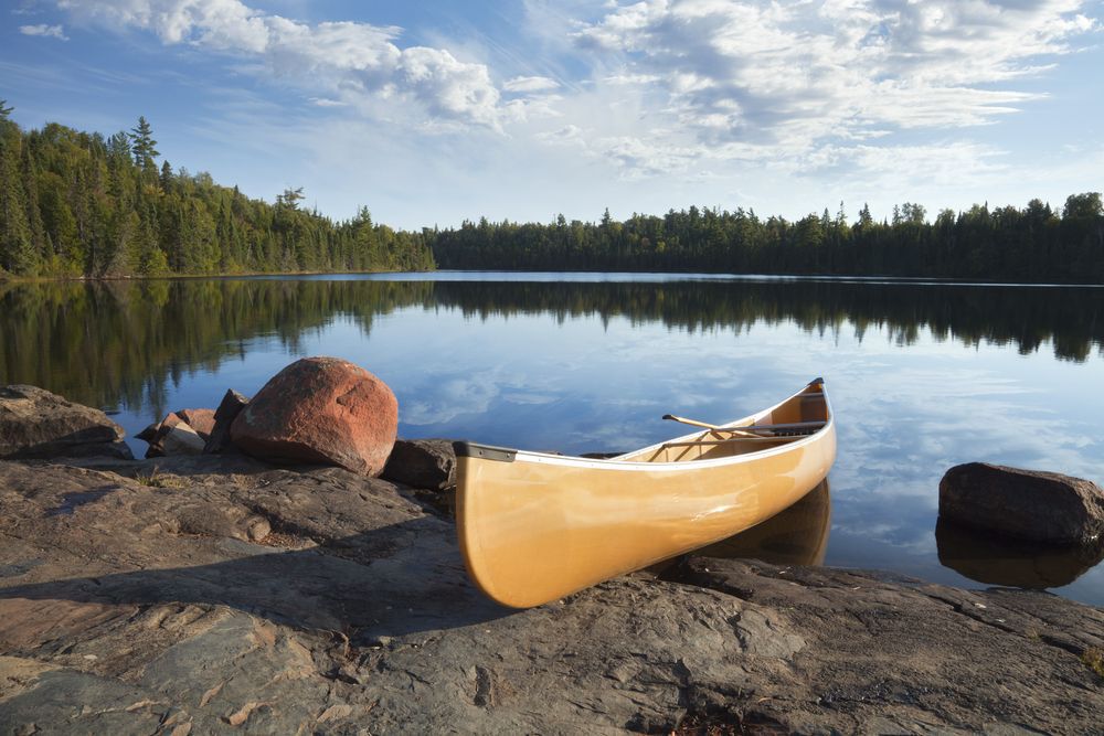 Wooden canoe on the rocky shore of a lake.