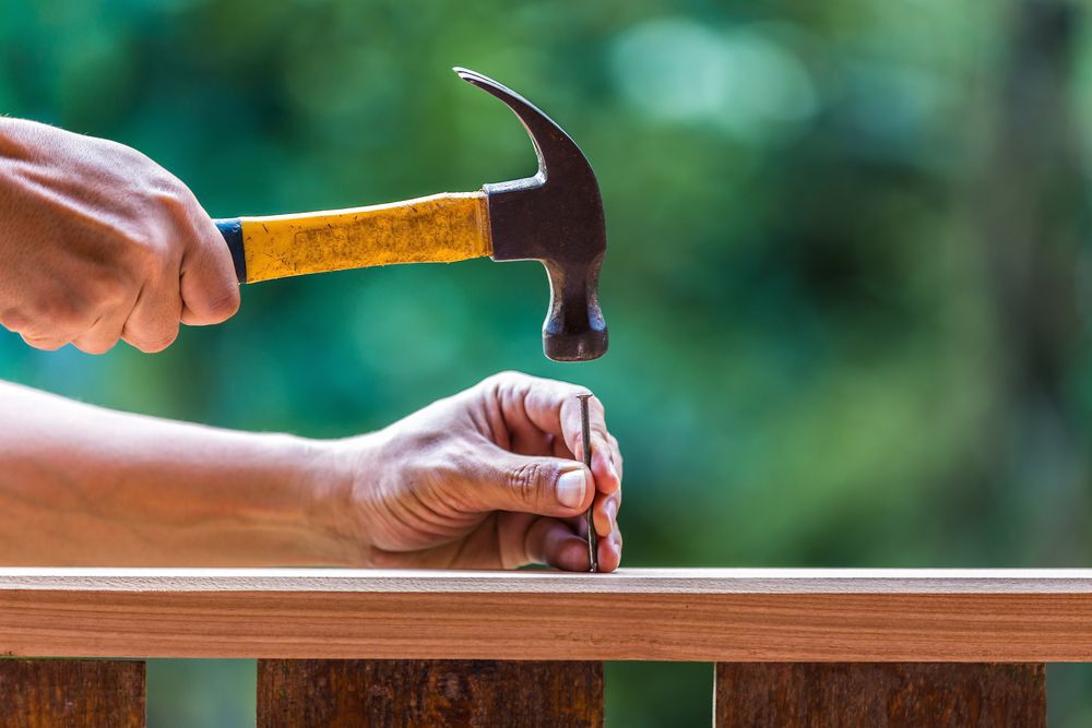 Person poised to hammer a nail into wood.