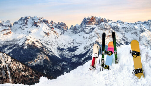 Skis and snowboards standing upright in a snowbank on a mountain.