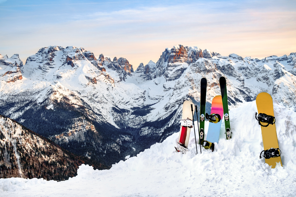 Skis and snowboards standing upright in a snowbank on a mountain.