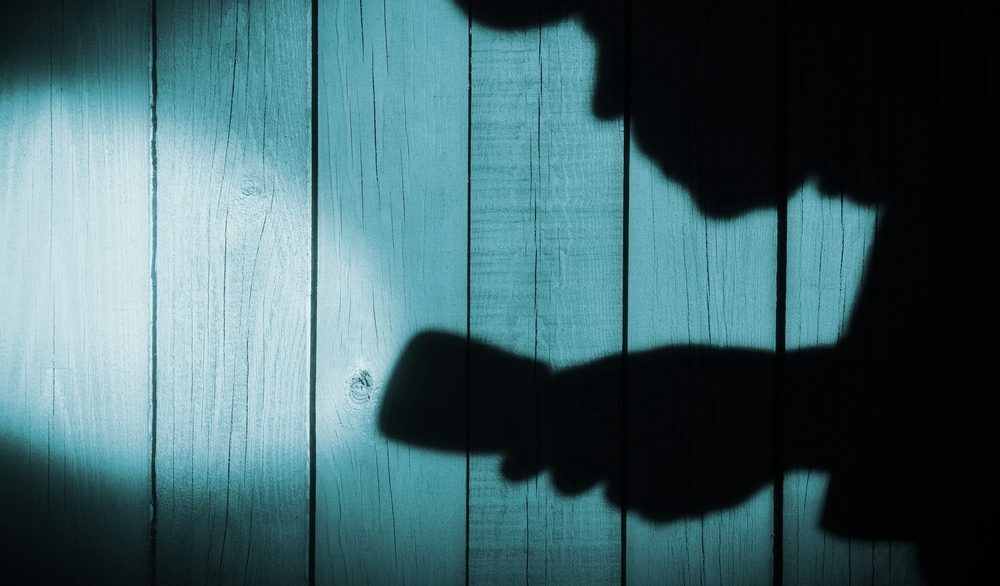 Shadow of a burglar holding a flashlight.
