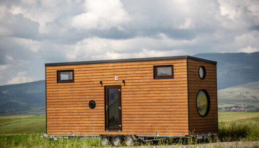 Tiny mobile house parked in a grassy field.