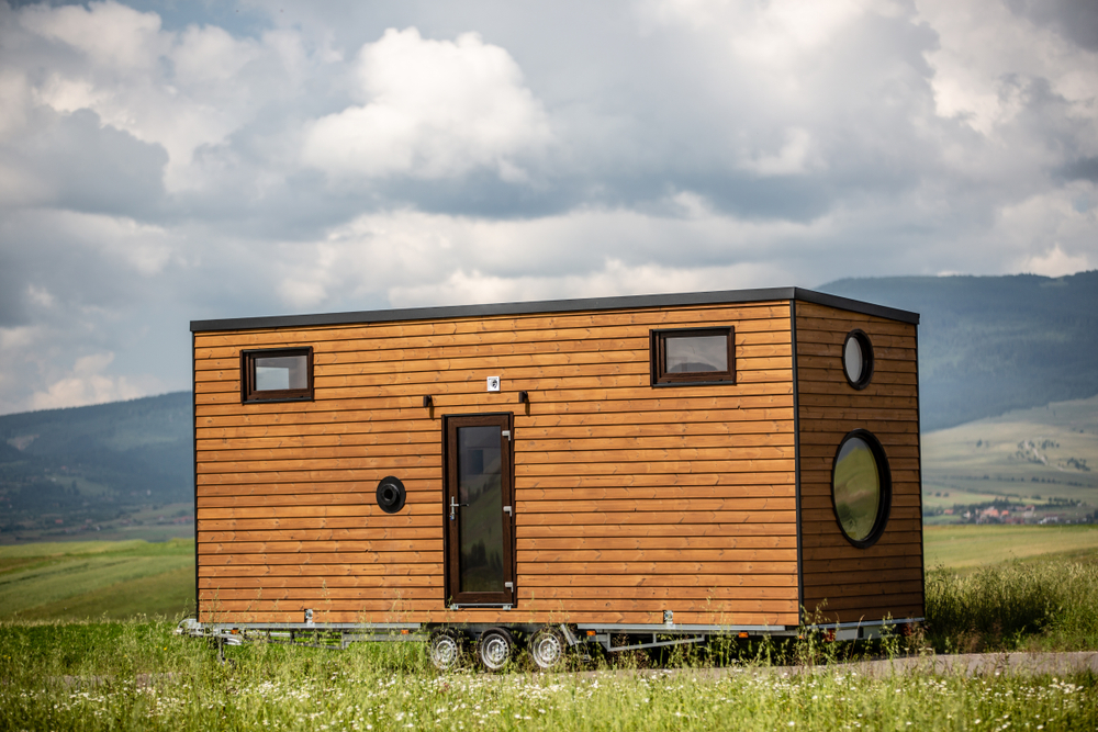 Tiny mobile house parked in a grassy field.
