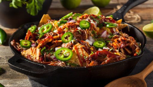 Loaded nachos in a cast iron pan.