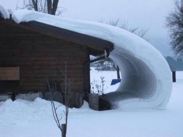 A wave of snow attached to a roof