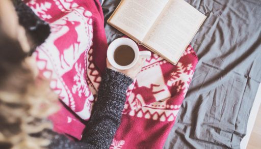 Person reading with tea and a blanket