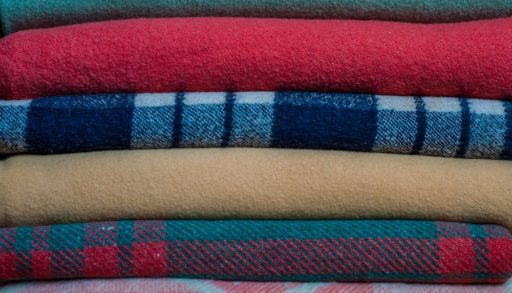 Patterned and coloured blankets stacked on top of each other.