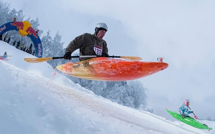 Person kayaking down a snowy hilll