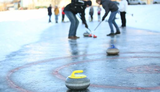 People curling outdoors on a frozen lake.