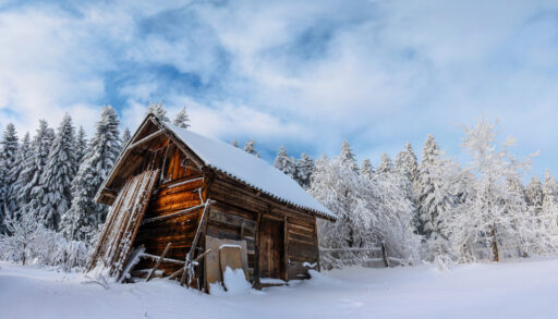 Lonely small wooden cabin in a snowy forest.