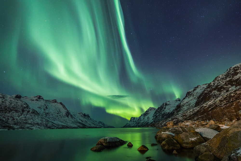 Northern lights above water and mountain landscape.