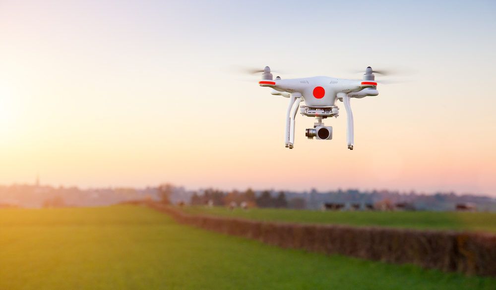 White and red drone hovering in the air at sunset.