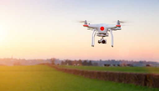 White and red drone hovering in the air at sunset.