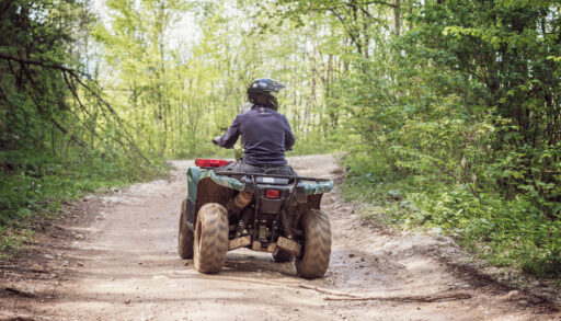 Man in a black helmet riding an ATV.