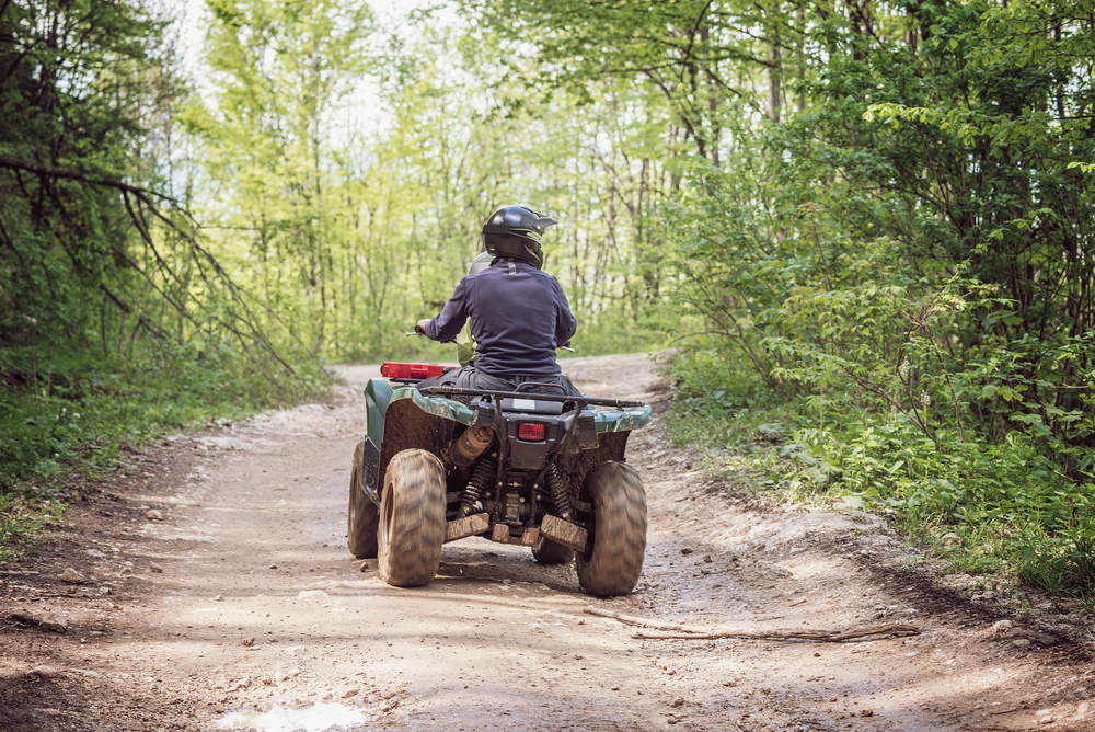 Man in a black helmet riding an ATV.