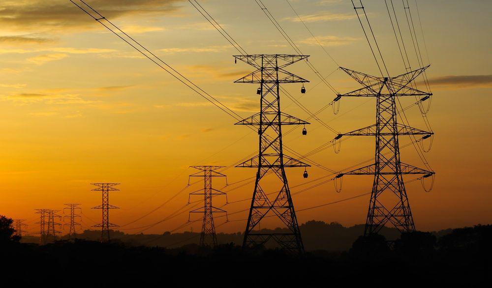 High voltage power towers and lines at sunset.