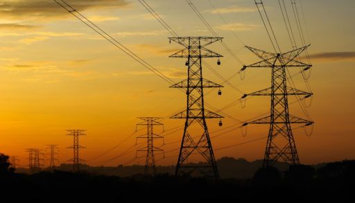 High voltage power towers and lines at sunset.