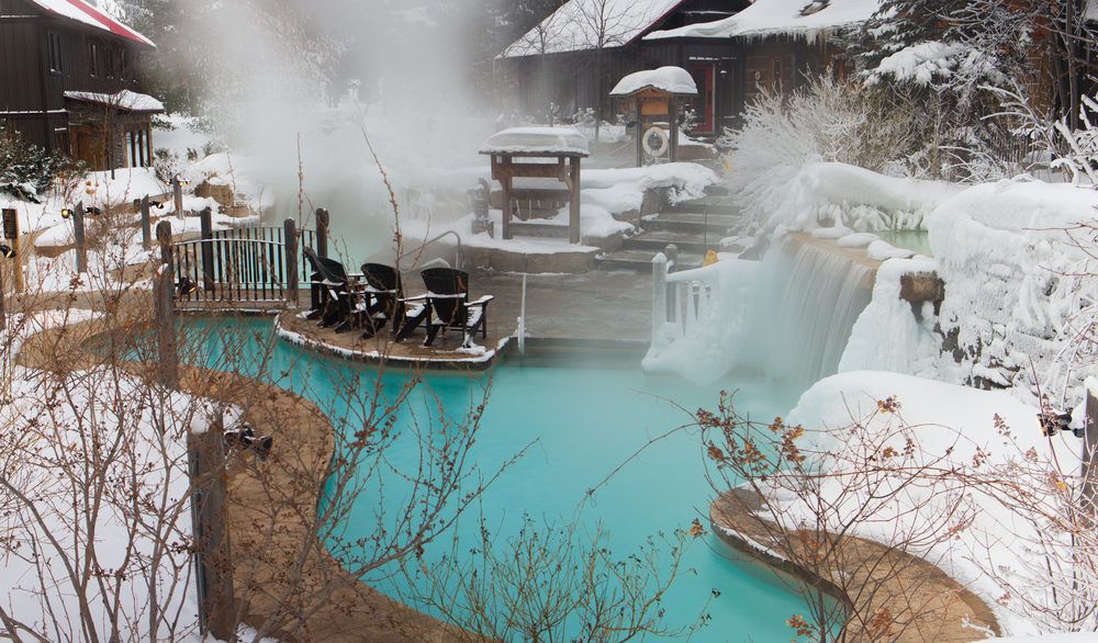Outdoor hot springs spa covered in snow.