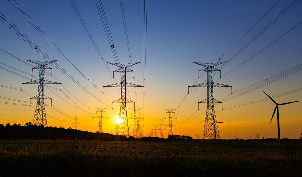 Sun setting behind hydro power towers and lines.