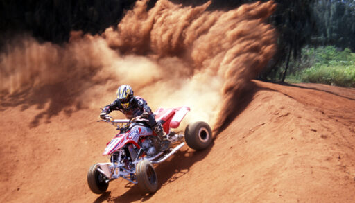 Person riding an ATV spraying up dirt.