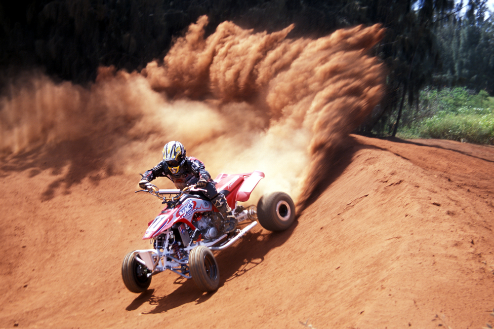 Person riding an ATV spraying up dirt.