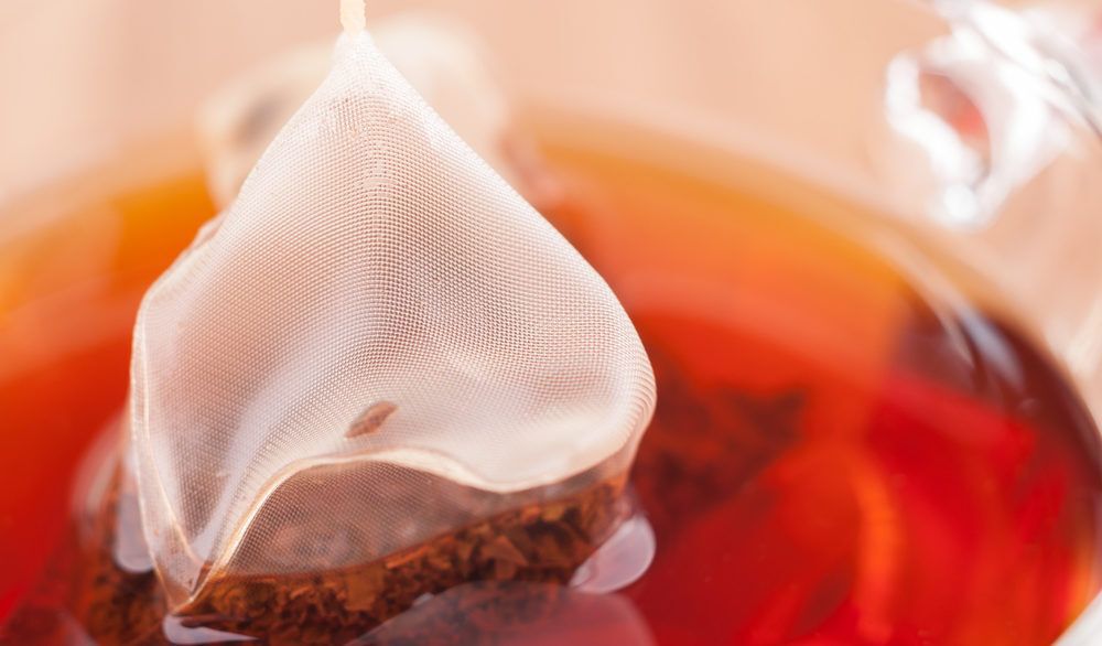 Mesh tea bag steeping in hot water.