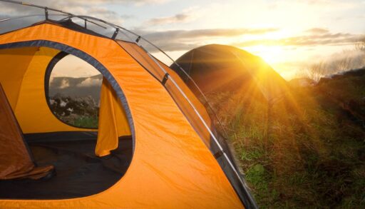 Orange tent on top of a mountain at sunset.
