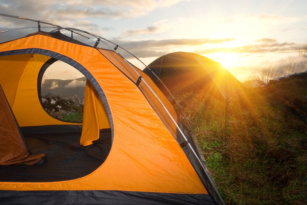 Orange tent on top of a mountain at sunset.