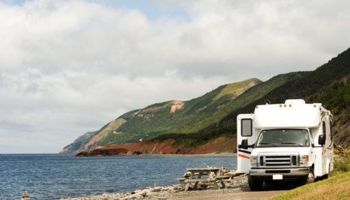 White RV trailer parked at a picnic area by the ocean in Cape Breton, Nova Scotia, Canada.