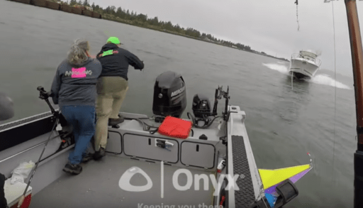 Three people preparing to jump off boat as another boat approaches