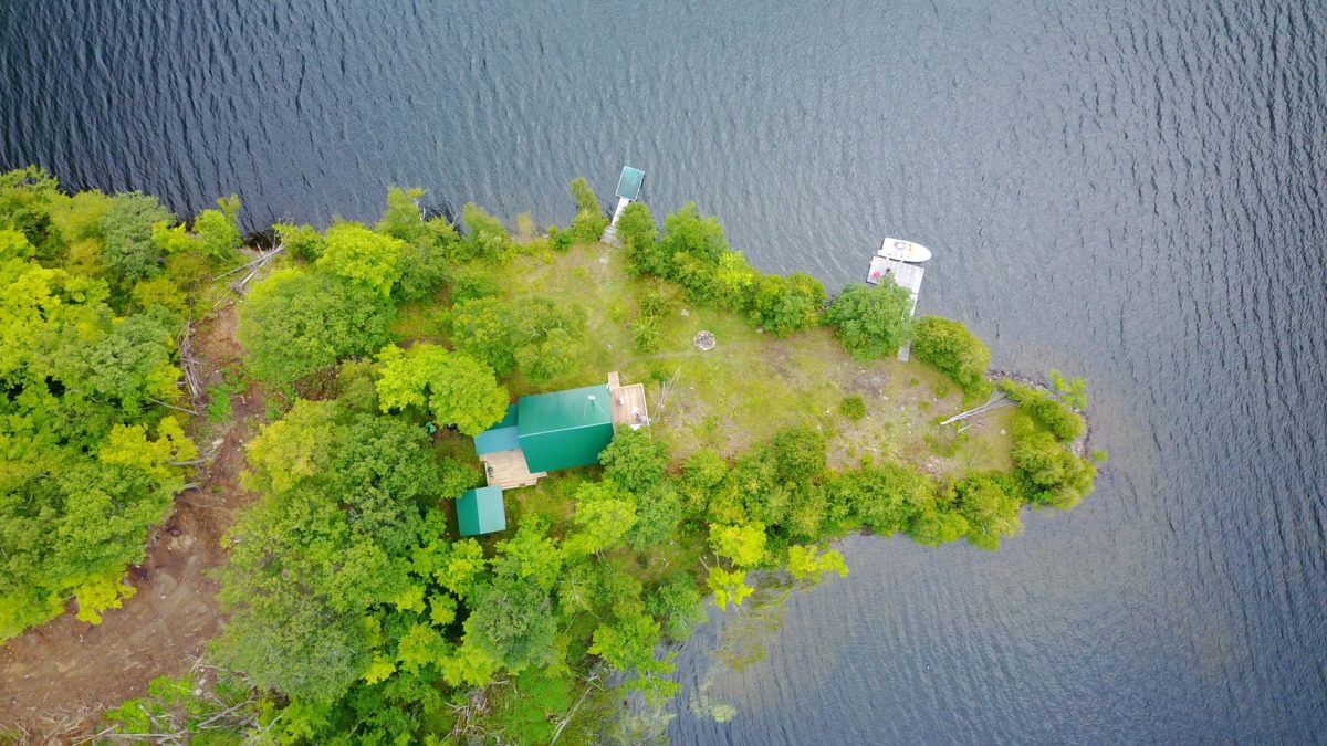 An aerial view of a cottage on a lake